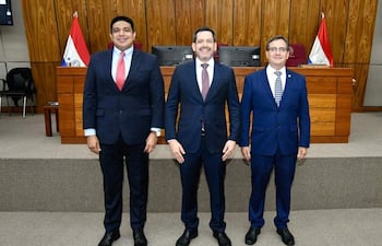 Raúl Latorre y Hugo Meza en trajes oscuros con sonrisas, flanquean a Pastor Vera en un ambiente legislativo oficial.