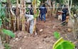 Hombre en traje de protección excavando en Caazapá, rodeado de policías que supervisan la escena con cintas amarillas de seguridad.