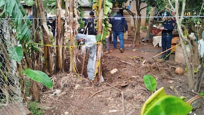 Hombre en traje de protección excavando en Caazapá, rodeado de policías que supervisan la escena con cintas amarillas de seguridad.