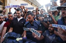 Varias personas con carteles que rezan "prensa" rodean el cuerpo del periodista Ismail al-Ghoul, de Al Jazeera, fallecido junto a su camarógrafo Rami al-Refee en un bombardeo israelí en el campo de refugiados de Al-Shati, en Gaza, el pasado 31 de julio.