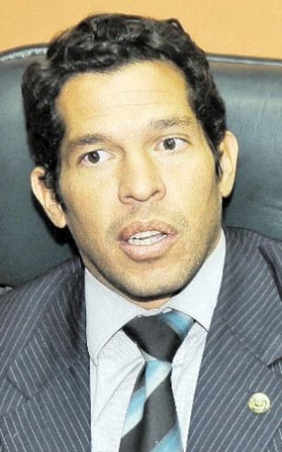 José Agustín Delmás, vestido con traje oscuro y corbata de colores, sentado con expresión seria en un entorno de oficina.