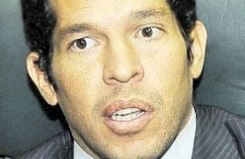 José Agustín Delmás, vestido con traje oscuro y corbata de colores, sentado con expresión seria en un entorno de oficina.