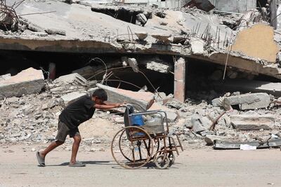 Un niño palestino usa una silla de ruedas para transportar botellas de plástico en el barrio Sheikh Radwan de la ciudad de Gaza el 24 de agosto de 2025.