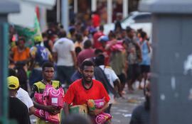 La gente lleva artículos mientras las multitudes abandonan las tiendas con bienes saqueados en medio de un estado de disturbios en Port Moresby el 10 de enero de 2024.