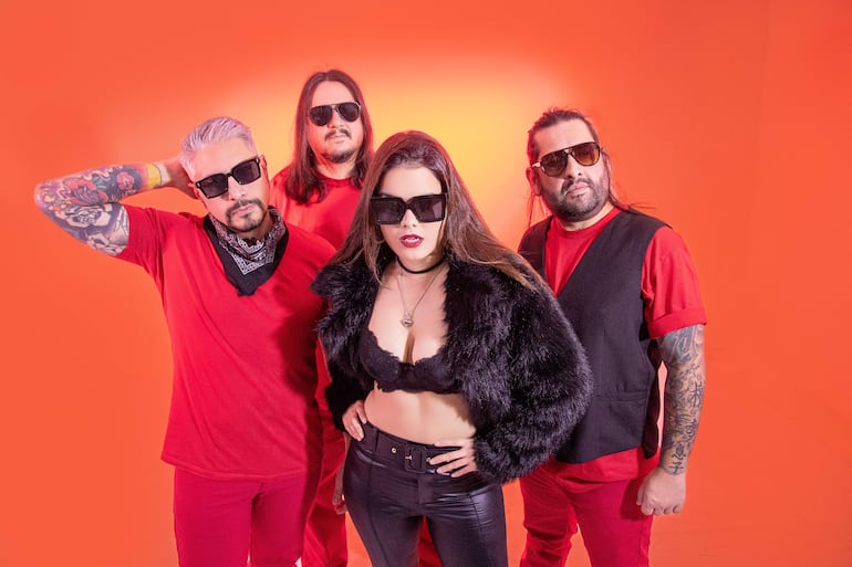 Cinco integrantes de Cielo Ámbar lucen ropa roja y lentes de sol, con una mujer en el centro que lleva top negro y chaqueta de pelaje.