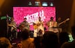 Cinco músicos en el escenario, con vestimentas tradicionales. Tocado el arpa, guitarras y acordeón en un ambiente festivo.