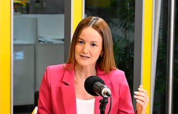 Soledad Núñez en blazer rosa conversando, gesticulando con una mano, frente a un micrófono y una taza en un ambiente de estudio.