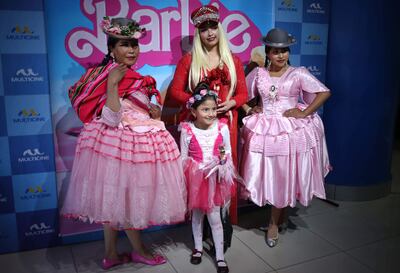Tres mujeres y una niña posan frente a un cartel del filme "Barbie", en La Paz (Bolivia).