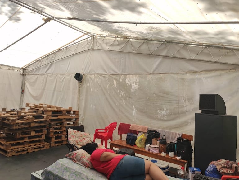 Familiar de un paciente descansa en el precario toldo instalado como albergue en el IPS Central.