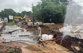 Obras viales en Santo Domingo con socavones llenos de agua y maquinaria de construcción en un día nublado y lluvioso.
