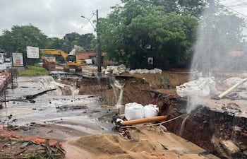 Obras viales en Santo Domingo con socavones llenos de agua y maquinaria de construcción en un día nublado y lluvioso.