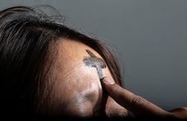 Un sacerdote marca la frente de una mujer con una cruz de ceniza.
