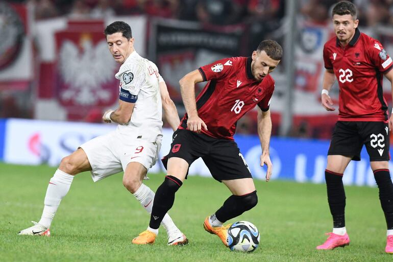 El polaco Robert Lewandowski disputa el balón con Ardian Ismajli, de la selección de Albania que ganó ayer por 2-0.