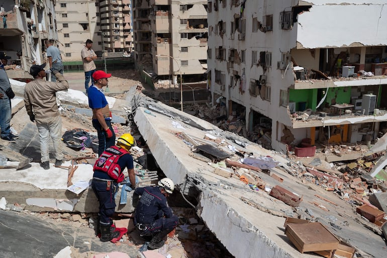 Personas realizan labores de búsqueda y remoción de escombros en edificios afectados por terremotos este jueves, en Catia La Mar (Venezuela).