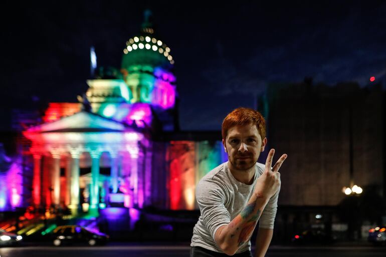 Una persona toma una fotografía frente al Congreso de la Nación Argentina iluminado, durante la conmemoración de los diez años del primer matrimonio igualitario en la Argentina.
