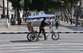 Una persona camina con un bicitaxi, en La Habana (Cuba).