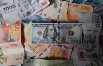 Fotografía de billetes de pesos argentinos y de 100 dólares americanos.