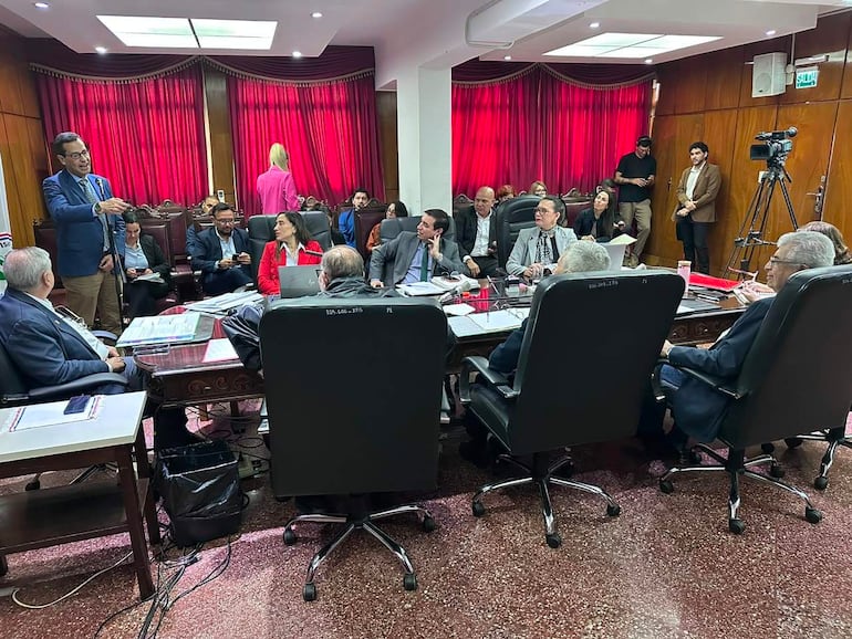 Isaías Fretes preside la sesión del IPS, mientras Carlos Duarte Reguera presenta su informe a los asistentes en ambiente formal.