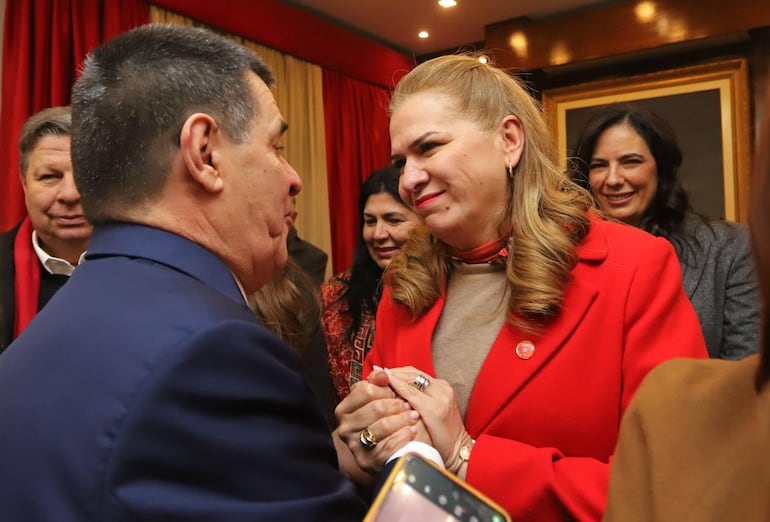 María Teresa Barán, de rojo, toma entre sus manos la mano de Horacio Cartes. De fondo, la ministra Claudia Centurión.