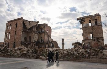 Los sirios pasan junto a una de las estructuras destruidas de Alepo cerca de la histórica ciudadela de la ciudad del norte el 5 de diciembre de 2024, el día en que las fuerzas rebeldes, lideradas por el grupo islamista Hayat Tahrir al-Sham (HTS), capturaron la ciudad central de Hama, casi una semana después. Los rebeldes sirios liderados por islamistas radicales entraron este jueves en Hama, tras combates con el ejército del presidente Bashar al Asad, que reconoció haber perdido esta ciudad estratégica del centro de Siria.