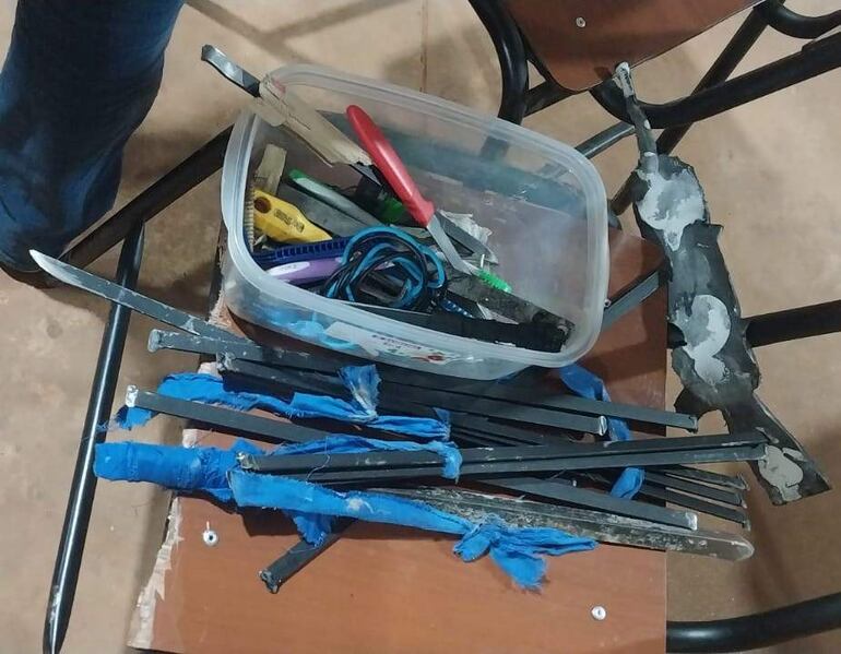 Mesa con cuchillo, hojas y elementos en caja plástica, en ambiente de trabajo sin personas visibles.