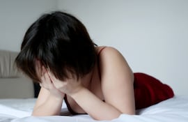 Mujer llora en su cama.