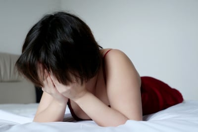 Mujer llora en su cama.