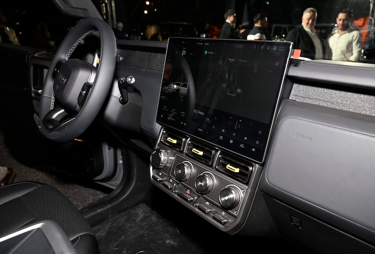 Interior de un vehículo con volante moderno y pantalla digital, sin personas visibles en la imagen.