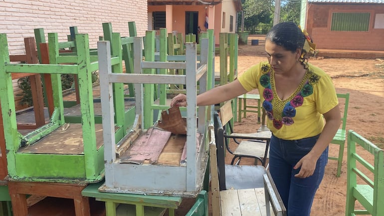 Rosalba Muñoz muestra, con gesto de frustración, los muebles enviados por el MEC a la escuela y colegio Presidente Coronel Rafael Franco, ubicada en la comunidad de Cristo Rey, km 186 de la ruta PY05.