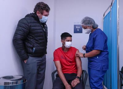 Jugador de Cerro Porteño, Miguel Martínez (c), mientras recibe la vacuna contra la covid-19 junto al presidente de la Confederación Sudamericana de Fútbol (Conmebol), Alejandro Domínguez (i).