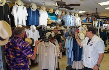 El vendedor Jhonny Cardona (d) habla con clientes, en una tienda en la Pequeña Habana, en Miami (Estados Unidos).