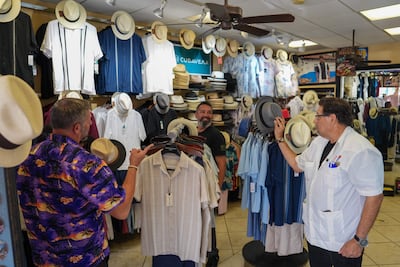 El vendedor Jhonny Cardona (d) habla con clientes, en una tienda en la Pequeña Habana, en Miami (Estados Unidos).