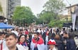 Multitud vestida de blanco y con banderas de Paraguay, enérgica en protesta, escuchando a un orador en una plataforma sobre un vehículo.