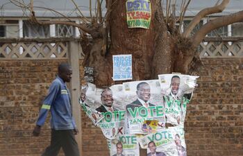 Un hombre pasa junto a los carteles de la campaña electoral del presidente de Zimbabwe, Emmerson Mnangagwa, en Harare.