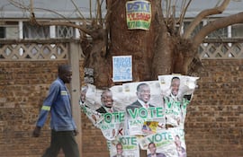 Un hombre pasa junto a los carteles de la campaña electoral del presidente de Zimbabwe, Emmerson Mnangagwa, en Harare.