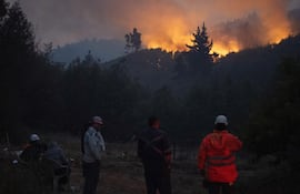 Personas observan un incendio forestal este lunes, en la comuna de Chaimávida, en Concepción a unos 491 km aproximadamente de Santiago (Chile).