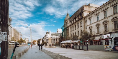 Bucarest, Rumanía. Amplia pasarela peatonal en la Plaza de la Universidad que muestra un monumento, arquitectura clásica, cafés al aire libre.