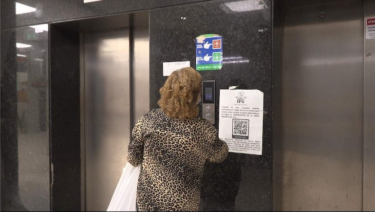 Mujer de cabello rizado y blusa de leopardo frente a un ascensor, lista para presionar el botón 'ER'.