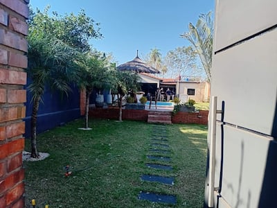 Entorno exterior de una vivienda, con plantas y caminos, en un día soleado y tranquilo.