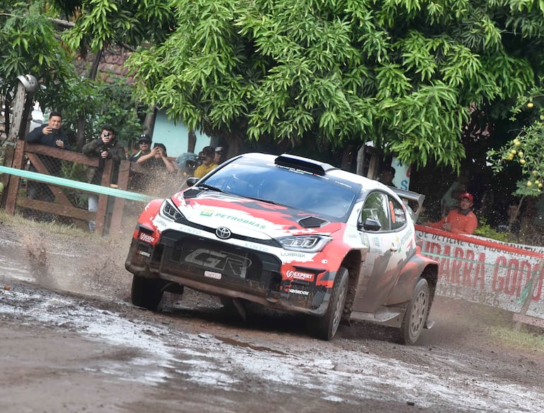 Toyota deslizándose en barro, levantando agua y barro, mientras el público observa con entusiasmo.