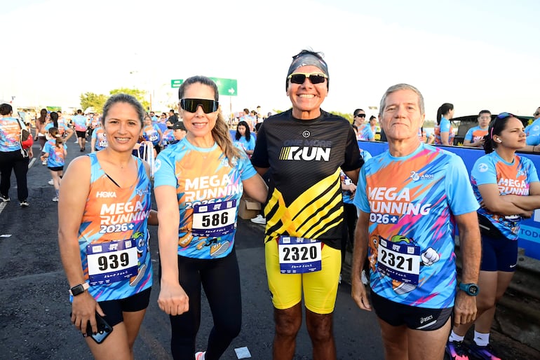 Cuatro personas con camisetas del evento Mega Running 2026, sonriendo y posando, en un ambiente festivo de carrera.