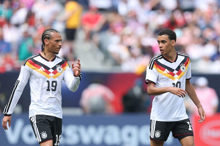 Leroy Sané de Alemania habla con su compañero de equipo Jamal Musiala durante el partido amistoso internacional entre Estados Unidos y Alemania en el Soldier Field, en Chicago.