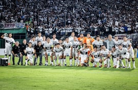 Los jugadores de Olimpia posan con la hinchada franjeada de fondo, tras obtener el boleto a la fase de grupos de la Copa Sudamericana, con el triunfo sobre Sportivo Trinidense.