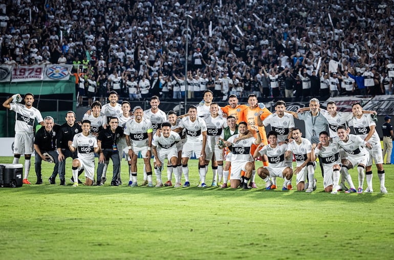 Los jugadores de Olimpia posan con la hinchada franjeada de fondo, tras obtener el boleto a la fase de grupos de la Copa Sudamericana, con el triunfo sobre Sportivo Trinidense.