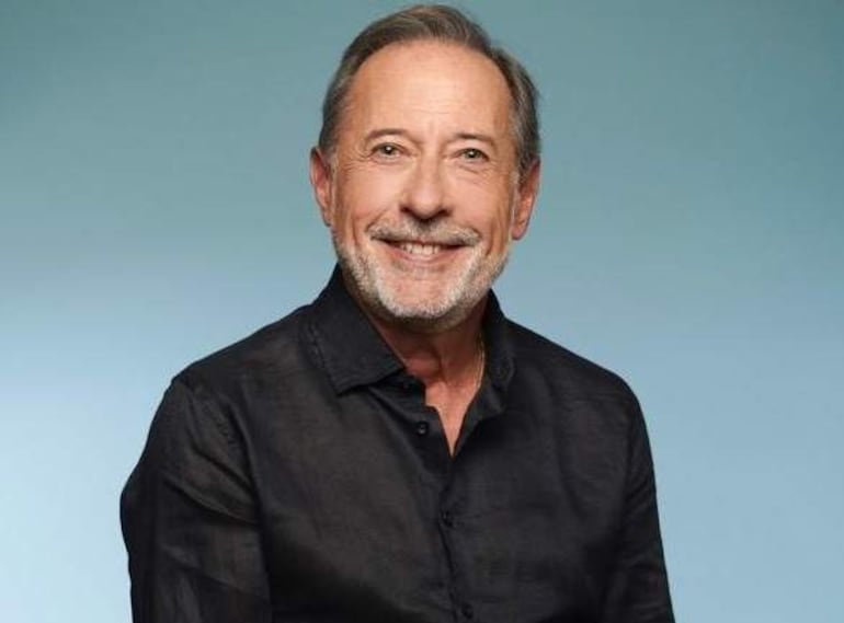 Guillermo Francella sonriente en retrato, con dimples visibles, destacando su expresión feliz en un ambiente elegante.