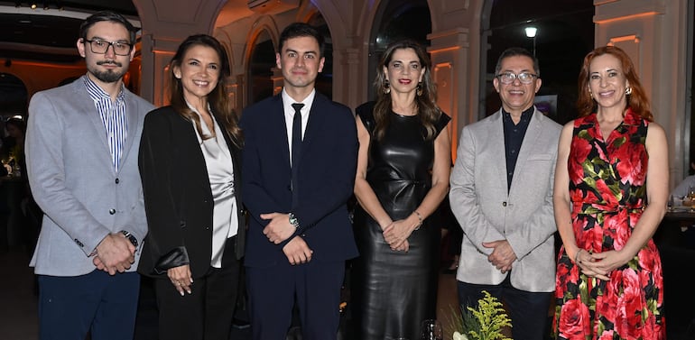 Seis personas bien vestidas, con un grupo de cuatro mujeres y dos hombres en un ambiente iluminado y formal.
