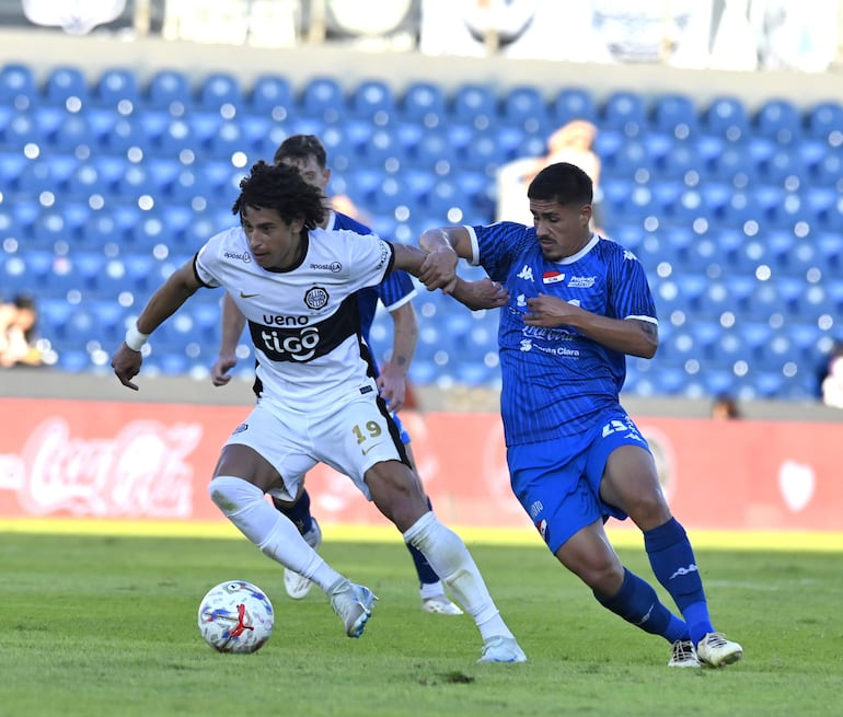 El delantero de Olimpia, Adrián Alcaraz intenta avanzar con el esférico ante la persecución del mediocampista de Nacional, Roberto Ramírez.