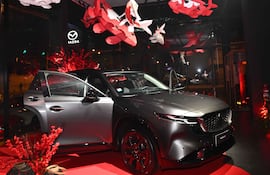 Vehículo Mazda CX-30 en alfombra roja, con puerta abierta y decoraciones rojas y blancas en un ambiente elegante.