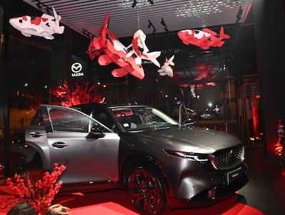 Vehículo Mazda CX-30 en alfombra roja, con puerta abierta y decoraciones rojas y blancas en un ambiente elegante.