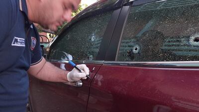 Un oficial de policía verifica los orificios de bala en la camioneta de Mario Aníbal Escobar (funcionario de la Ande), en Pedro Juan Caballero.